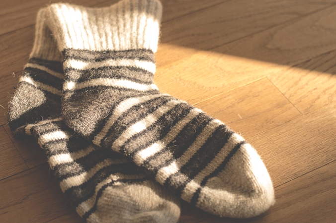 Two knitted socks laying on wooden floor